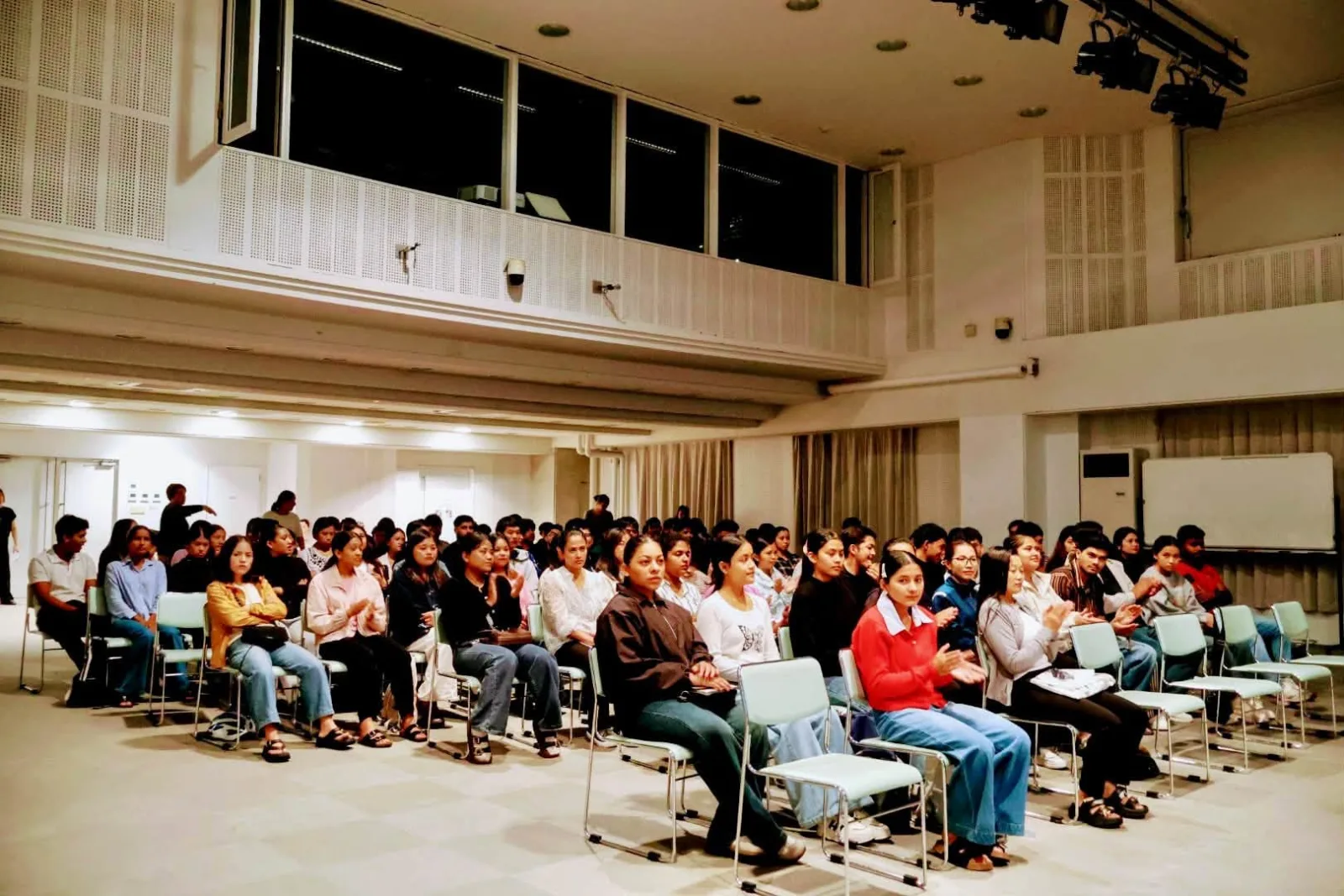 A hall of students seated in rows of chairs facing the stage at the new-student orientation