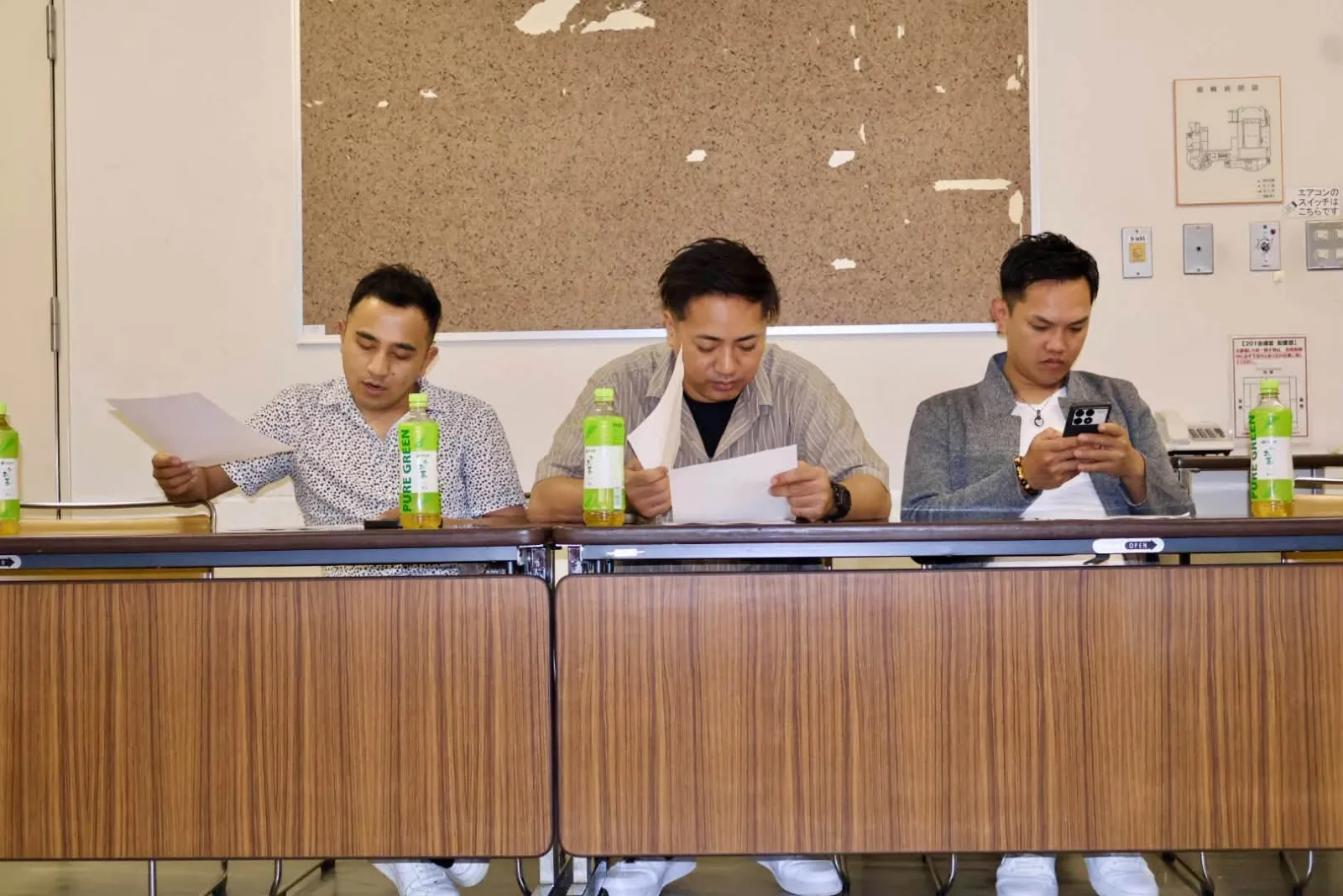 Three members reading through papers at the top table during a Senpai Kai session